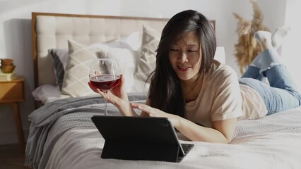 Happy beautiful woman in casual clothes talking on video call on digital tablet lying on the bed. Playing game shopping online relaxing. - Powered by Adobe
