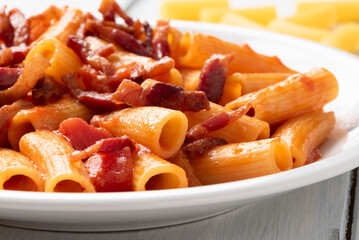 Rigatoni all'amatriciana, tipica ricetta laziale di pasta condita con salsa di pomodoro e...