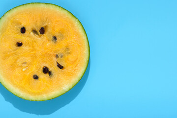 fresh sliced yellow watermelon, flat lay with hard shadow on blue background, creative decoration of summer concept, copy space