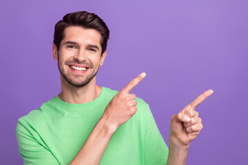 Photo of positive optimistic man with stubble green t-shirt indicating at discount empty space isolated on purple color background