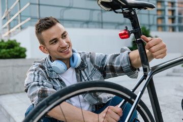 Obraz premium Good-looking young man fixing a problem with a bike tire