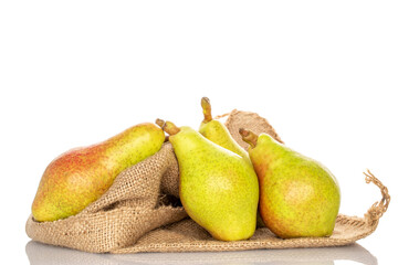 Three organic green pears on a jute bag, close-up, on a white background.