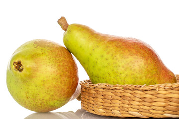 Two ripe organic green pears in a straw plate, close-up, on a white background.