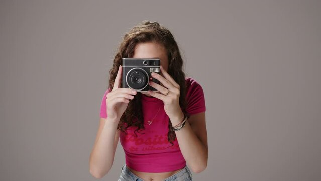 Caucasian brunette brings instant film camera up to face to take picture