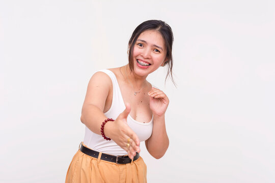 A friendly young Asian woman extending hand to offer a handshake as a nice to meet you gesture. Isolated on a white background.