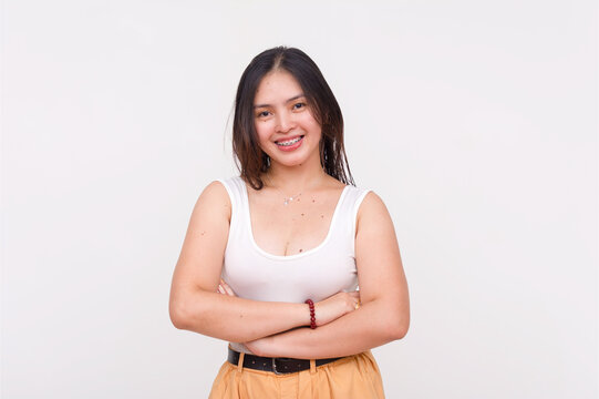 A sweet and charming young Asian woman with braces smiling with arms crossed. Isolated on a white background.