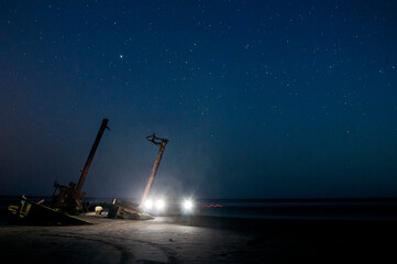 Night sky with stars and a shipwreck on the beach. Long exposure.