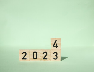 New Year 2024. wooden blocks of 2024 on a green background. Concept Start the new year by achieving...
