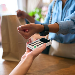 Close Up Of Female Customer In Fashion Store Making Contactless Payment With Smart Watch