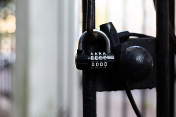 Black metal lock with a letter code hangs from a closed black metal door. Protection and personal...