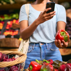 Close Up Of Female Customer At Market Stall Taking Photo Of Fresh Bell Pepper On Mobile Phone
