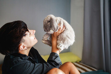 Woman with rabbit having tender moment at home - Owner and pet animal family friendship