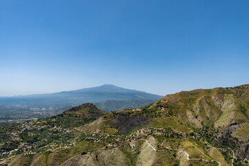 Fototapeta na wymiar Aerial view from Castelmola, Sicily on coastal town and natural mountainous landscape