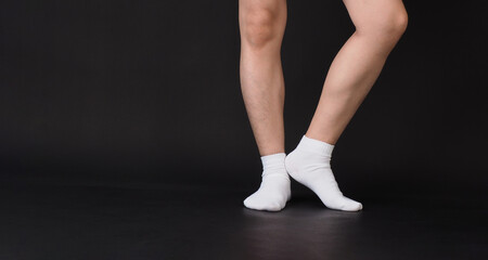 Asian Male legs wear white sock on black background.