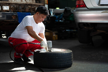 mechanic worker fixing tire with old car in garage