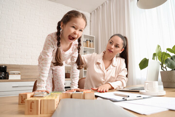 Working mother with her naughty little daughter in kitchen