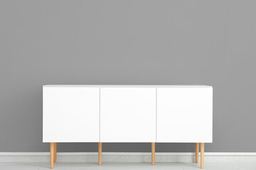White chest of drawers near grey wall in room