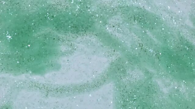Macro Shot of Gold Particles made of Powder, Cosmetic Texture in Water Descend up on White Background. Slow Motion. Production of Natural Cosmetics. High quality FullHD footage