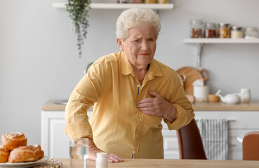 Senior woman having heart attack in kitchen