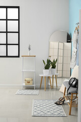 Interior of stylish hallway with mirror, grey bench and shelving unit