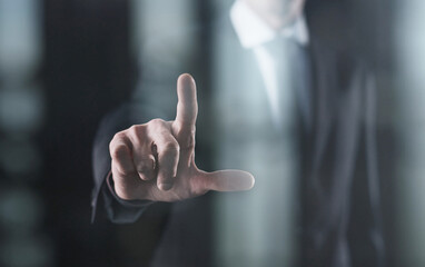Focused businessman pointing with finger on dark background