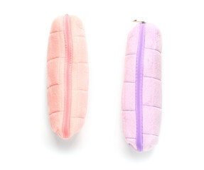 Pink and purple pencil cases on white background