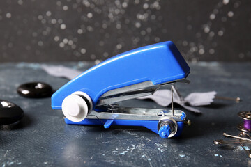 Manual sewing machine with different supplies on grunge black table near wall