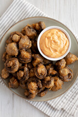 Homemade Crispy Deep Fried Mushrooms with Spicy Mayo on a Plate on a white wooden background, top view.