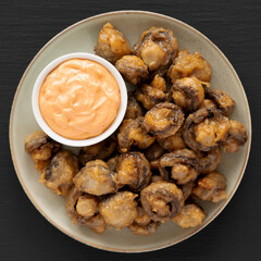 Homemade Crispy Deep Fried Mushrooms with Spicy Mayo on a Plate on a black background, top view.