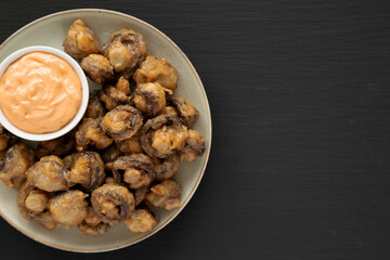 Homemade Crispy Deep Fried Mushrooms with Spicy Mayo on a Plate on a black background, top view. Copy space.