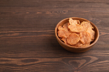 Slices of dehydrated salted meat chips on brown wooden, side view, copy space