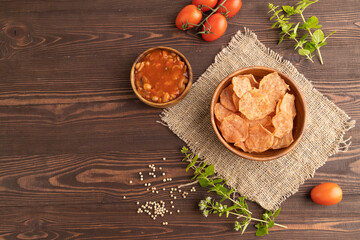 Slices of dehydrated salted meat chips on brown wooden, top view, copy space