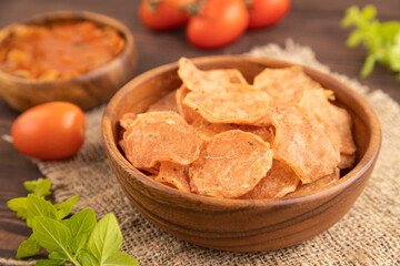Slices of dehydrated salted meat chips on brown wooden, side view, selective focus