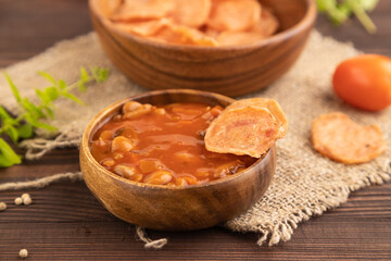 Slices of dehydrated salted meat chips on brown wooden, side view, selective focus