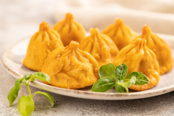 Manti dumplings with pepper, basil on gray concrete. Side view, selective focus