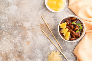 Tteokbokki or Topokki, fried rice cake stick, on gray concrete, top view, copy space