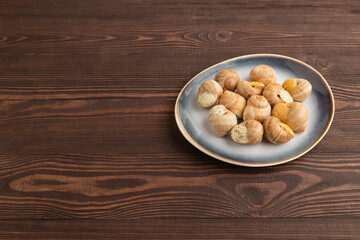 Grape (Burgundy) snails with butter and cheese on brown wooden, side view, copy space.