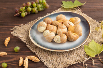 Grape (Burgundy) snails with butter and cheese on brown wooden, side view