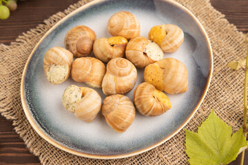 Grape (Burgundy) snails with butter and cheese on brown wooden, side view, selective focus