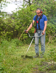 lawn trimming with hand petrol mower. work on mowing tall grass with lawn trimmer in backyard