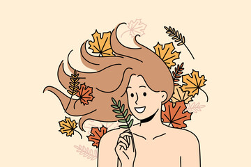 Woman with long flowing hair lies among autumn leaves and smiles rejoicing at onset of september. Woman with bare shoulders for advertising cosmetics or shampoo made on basis of herbs and plants