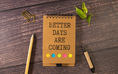 On the table are gears, pencils and a notebook with the inscription - Better Days Are Coming.