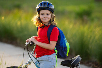 Obraz premium Child on bicycle. Boy in a helmet riding bike. Little cute caucasian boy in safety helmet riding bike in city park. Child first bike. Kid outdoors summer activities. Kid on bicycle. Boy ride a bike.