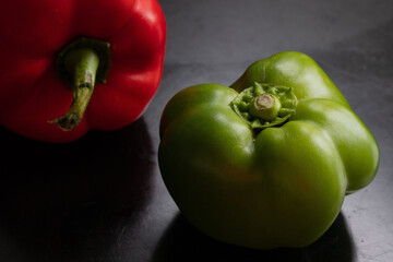 green and red peppers on a wooden board. Salad preparation Black background. Vegetable with kitchen board on black background in rustic style