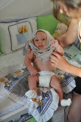 mãe colocando roupa em bebê em casa 