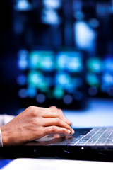 Close up shot of manager in server hub using laptop to set up configuration management tools that...