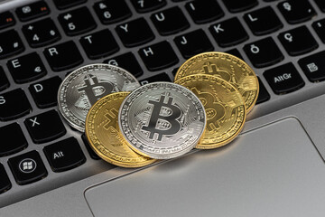 Golden and silver bitcoin isolated on keyboard.