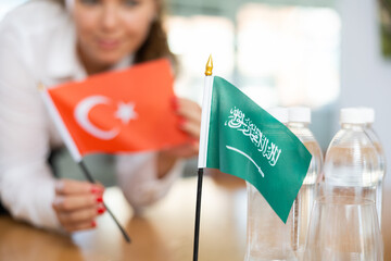 Little flag of Saudi Arabia on table with bottles of water and flag of Turkey put next to it by...