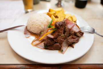 Lomo saltado Peruvian food salted beef with tomatoes, onion, fried potatoes and rice.