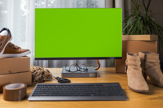 online footwear store mockup, computer monitor with blank green screen on the desk at home. SME business